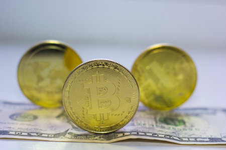 Three cryptocurrency coins on a dollar bill close-upの写真素材