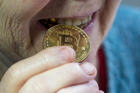 Elderly woman, grandmother holds a bitcoin coin in her teethの写真素材