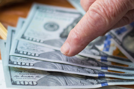 The female hand of an elderly woman points her finger at the dollarの写真素材