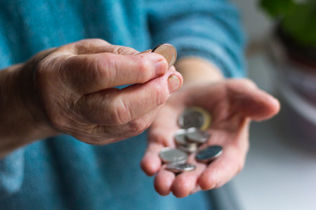 Grandmas wrinkled hands hold change in poverty
