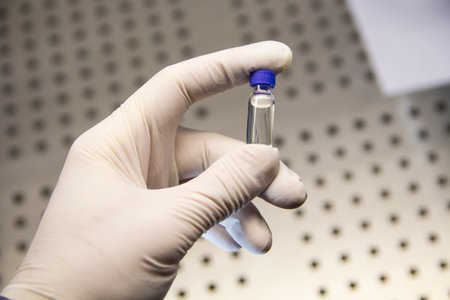 Hand of an expert in a rubber glove holding a vial close-upの写真素材