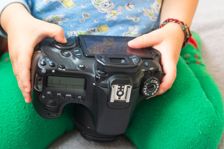 Toddlers hands hold a camera and press buttons close-up