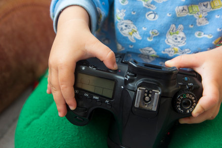 Toddlers hands hold a camera and press buttons close-upの写真素材