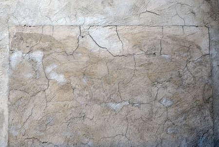 Gray plastered wall covered with cracksの写真素材