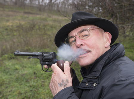 Man with gun  system Nagan smoking his pipe