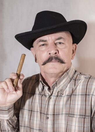 The cowboy with mustache, in a black hat smoking a cigarの写真素材
