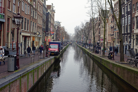 Amsterdam, Nederland- December 30,2016: Along the canal walk citizens and moving vehiclesのeditorial素材