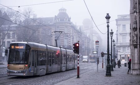 Brussels, Belgium-December 31,2016:Trams moving on rails. Pedestrians walk on the sidewalk.Weather is cloudyのeditorial素材