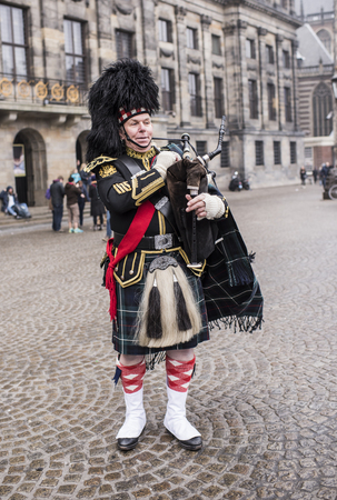 Amsterdam,Netherlands-December 30,2016:Bagpiper with his bagpipe in the square. Nearby are walking touristsのeditorial素材