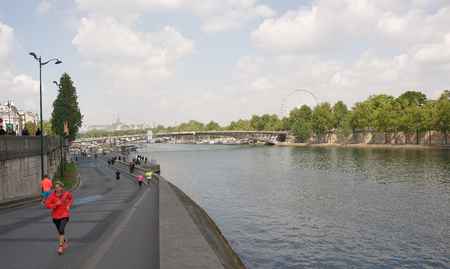 Paris,France- April 29,2017:Athletes run along the Port de Solferino.People walk around.In the foreground runs a lady in a red suitのeditorial素材