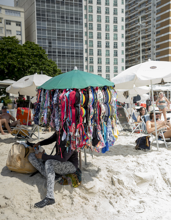 Rio de Janeiro, Brasil- March 05,2019: Seller bra rests. Citizens sunbathe and relax on Copacabana Beachのeditorial素材