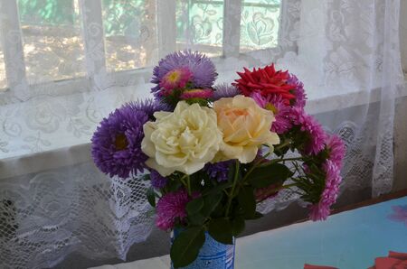 Beautiful bouqet with rose flowers and peony in vase on tableの写真素材