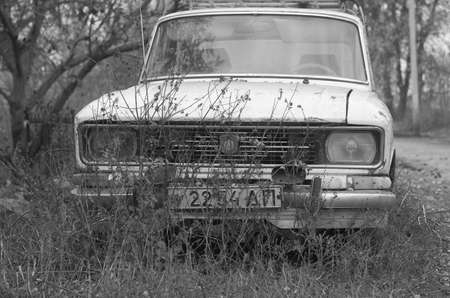 An old, damaged soviet car on the background of countryside in autumnの写真素材