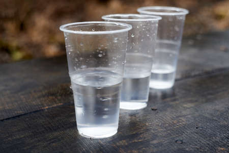 three plastic glasses with water on a wooden table