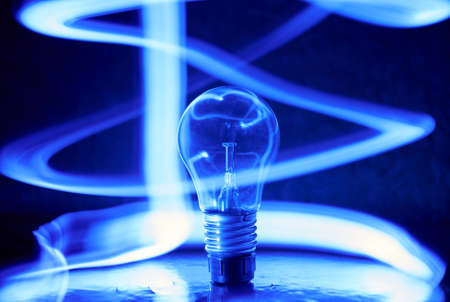 Photo of lightbulb with blue spiral light in the darkの写真素材