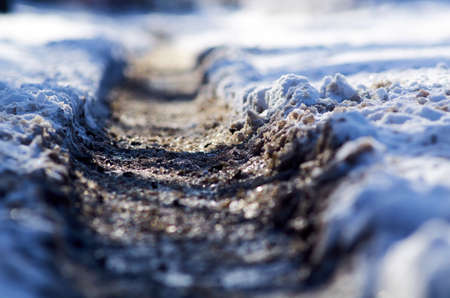 Car tire track on snowy road. winter returnsの写真素材