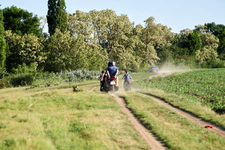 Teplyk, Ukraine - June 03, 2022: Teenagers on scooters drove along a rural road in the eveningのeditorial素材