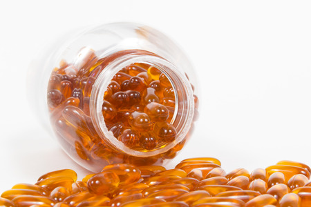 Fish oil capsules and container on white backgroundの写真素材