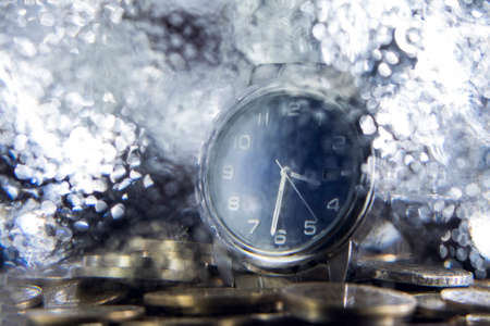 Hand Watch on top of coins behind a frozen displayの写真素材