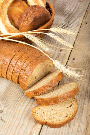 Slices of bread with wheat on a wooden surfaceの写真素材