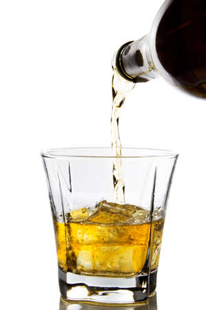 Whiskey being poured in a glass on white backgroundの写真素材