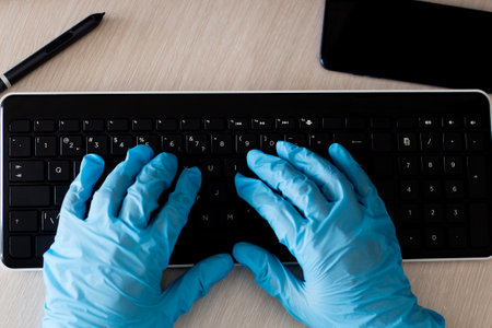 the computer keyboard and hands in protective glovesの写真素材