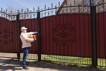 the volunteer with a box of food at the door of the houseの写真素材