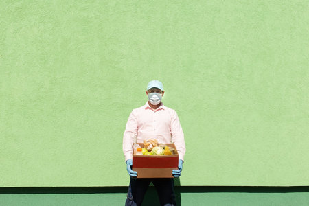 the volunteer with products in a protective mask and glovesの写真素材