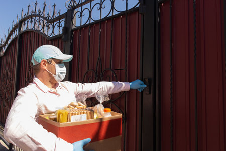 the volunteer with a box of food at the door of the houseの写真素材