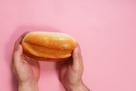 the bread in hand on a pink backgroundの写真素材