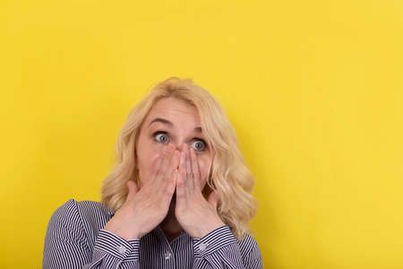 the blonde covered her face with her hands, surprisedの写真素材