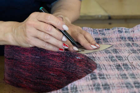 Women's hands on a sewing industrial workplace. Cut the fabric.の写真素材