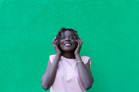 the beautiful African American in headphones dancing, against a green backgroundの写真素材