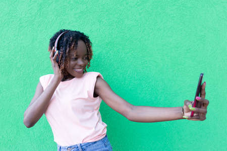 Beautiful African American takes a selfie, against a green background