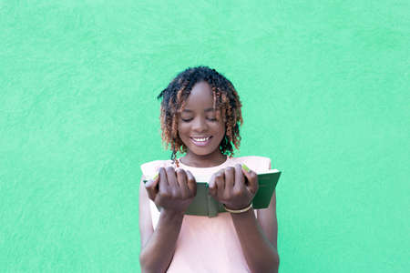 the beautiful African American with a book on a green background, a studentの写真素材