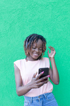 the Beauty African-American woman with phone on green background, studentの写真素材