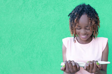 the Happy African-American woman with a book on a green background, a studentの写真素材
