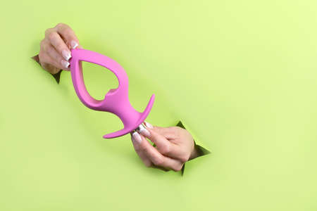 Toys for adults in delicate female hands on a green background. Lifestyle for adults.の写真素材
