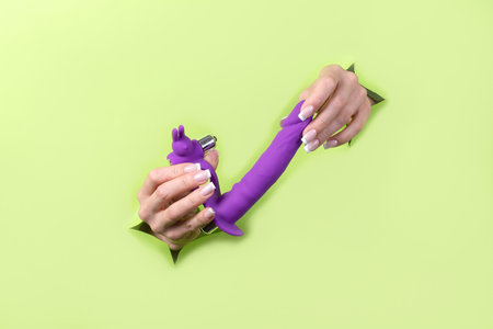 Toys for adults in delicate female hands on a green background. Lifestyle for adults.の写真素材