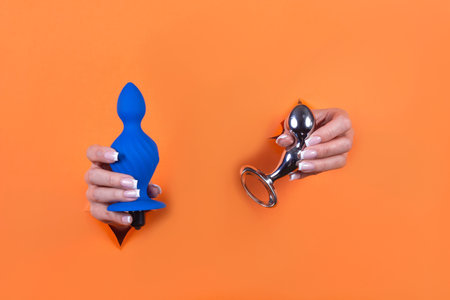 Adult sex toys in women's hands on an orange background.の写真素材