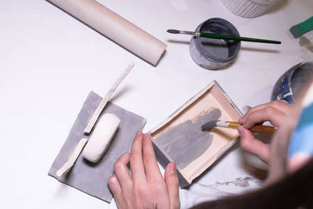 Children's hands in a pottery art workshop draw their work from ceramic clay.