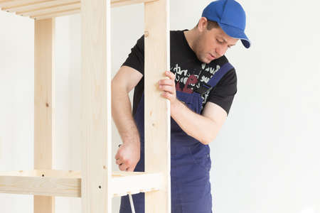A professional carpenter makes a product from wooden boards and slats. Carpentry and manufacturing.