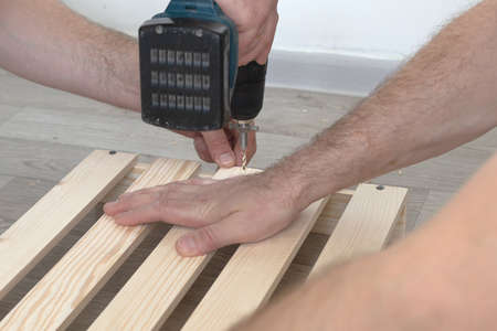 Wooden slats and working tools. Carpentry work. The self-tapping screw is screwed into the wooden...
