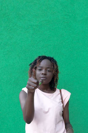 Young beautiful African American woman on a green background. Human emotions.の写真素材
