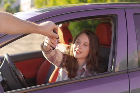 The girl takes the car key. Car sales and rentals.