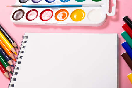 An album, colored pencils, paints and markers on a pink background. Subjects for drawing and school.の写真素材