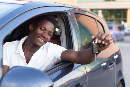 An African-American man holds a car key in his hands. Buying and renting a car.の写真素材