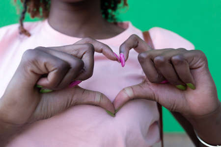 Happy and beautiful African American shows heart with her handsの写真素材