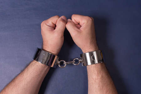 Men's hands in iron handcuffs. Sex toys.