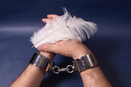 Male hands in handcuffs on a blue background. Sex toys.の写真素材